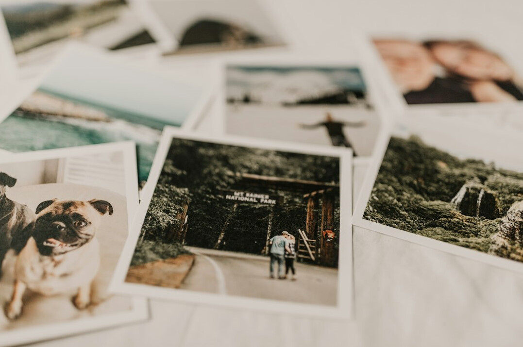 Photographer reviewing printed contact sheets and photographs on a wooden desk
